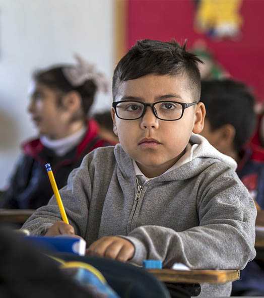 Child sitting at a desk in a classroom.